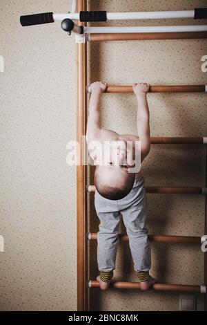 Heimtraining. Der Junge hängt den Kopf nach unten auf die horizontale Stange. Stockfoto