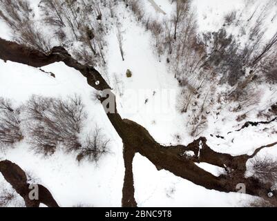 Ein paar Touristen wandern im Bergtal mit Fluss und Schnee zur Winterzeit in Almaty, Kasachstan. Luftaufnahme von oben, Drohnenaufnahme. Stockfoto