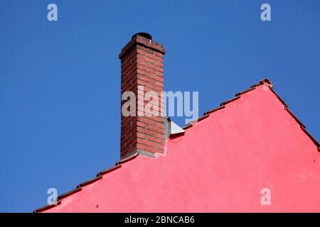 Dach, Kamin, rosa Hauswand, Dachkante, blauer Himmel Stockfoto