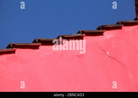 Dach, rosa Hauswand, Dachkante, blauer Himmel Stockfoto