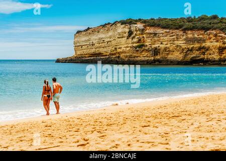 Junges Paar genießt schönen Sandstrand mit Klippen in Algarve, Portugal Stockfoto