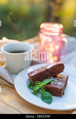 Kaffeetasse mit einem Schokoladenkuchen Kuchen auf einem Tisch im Freien Stockfoto