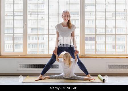 Junge Mutter macht einige Dehnungsübungen mit ihrer Tochter Stockfoto