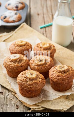 Bananenmuffin, Seitenansicht, vertikal. Cupcakes auf alter Leinenserviette, rustikaler Holztisch Stockfoto