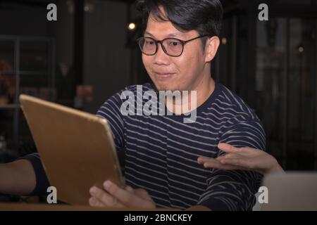 Ein attraktiver asiatischer smart und gut aussehende männliche Gesicht, junge Erwachsene Mann mit dunklen Haaren Porträt tragen Augen Glas und halten Sie die Tablette für das Konzept der hoch Stockfoto