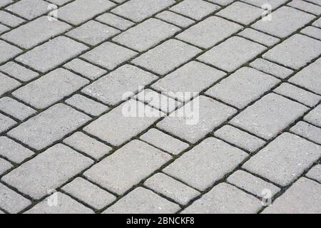 Struktur der grauen Pflasterplatten. Diagonale Linienfliesen für den Hintergrund des Fußpfads. Verlegung von Fliesen auf Wegen im Stadtpark. Stockfoto