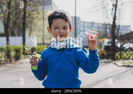 POSEN, POLEN - 17. Apr 2020: Junger polnischer Kaukasischer Junge, der Seifenblasen auf einer Straße erzeugt. Stockfoto