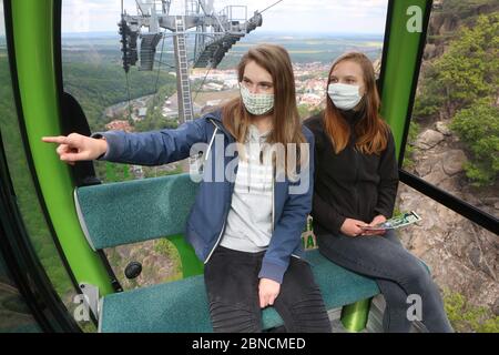 14. Mai 2020, Sachsen-Anhalt, Thale: Zwei Schülerinnen aus dem Harz sitzen mit Gesichtsmasken in einer Gondel der Talbahn. Die 21 Kabinen der Seilbahn bewegen sich nach der Suspendierung aufgrund der Corona-Pandemie erstmals wieder. Mehr als 680,000 Besucher fahren jährlich mit der Seilbahn zum Hexentanzplatz. Foto: Matthias Bein/dpa-Zentralbild/ZB Stockfoto