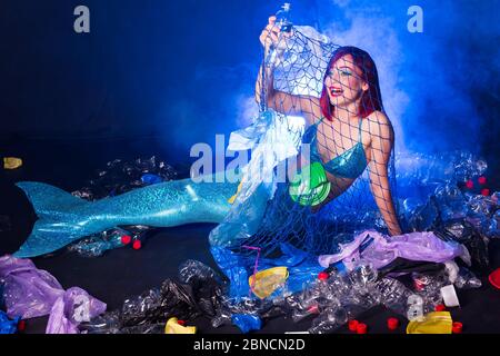 Fantasie dumme Meerjungfrau im tiefen Ozean. Plastikmüll und Flaschen Verschmutzung im Meer. Ökokatastrophe, Müll- und Kunststoffrecycling-Konzept. Stockfoto