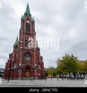 Panoramablick auf die hohe Johanniskirche (Johanneskirken) in Bergen, Norwegen. Gotische Kirche mit roten Backstein- und Kupferdetails. Wolkiger Herbsttag Stockfoto