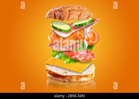 Leckeres Sandwich. Sandwich mit fliegenden Zutaten auf orangefarbenem Hintergrund isoliert. Stockfoto