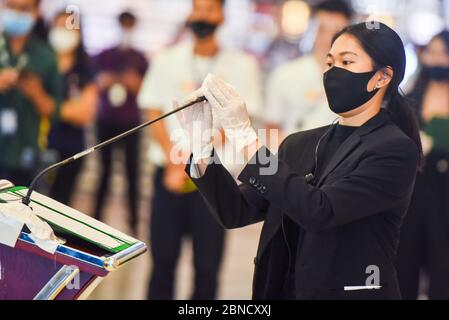 Ein Mitarbeiter von Siam Paragon, der eine Gesichtsmaske trägt, reinigt und desinfiziert das Mikrofon vor der Pressekonferenz während der Coronavirus-Pandemie. Nach zwei Monaten Stilllegung Thailands aufgrund der Covid-19-Krise. Die Einkaufszentren werden am 17. Mai mit strengen Gesundheits- und Sicherheitsmaßnahmen wieder für die Öffentlichkeit zugänglich gemacht. Stockfoto