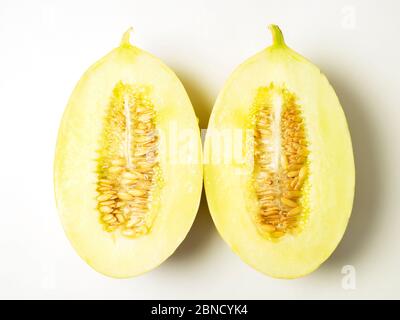 Zwei Hälften einer kanarienmelone mit Samen auf weißem Hintergrund Stockfoto