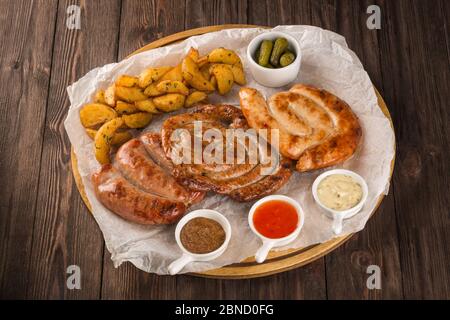 Verschiedene gegrillte Würstchen auf einem Holzbrett. Stockfoto