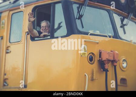 Retro Vorderansicht Nahaufnahme, britische Vintage-Diesellokomotive, die Station verlässt, Severn Valley Heritage Railway, Großbritannien. Zugfahrer winkt vom Fenster der Kabine. Stockfoto