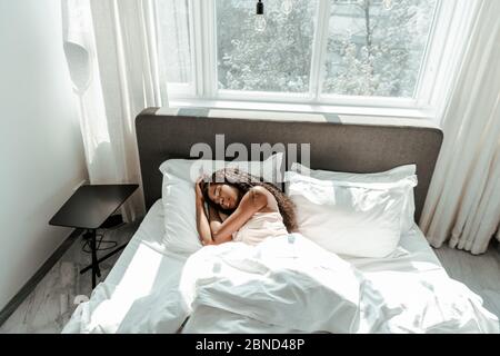 Blick aus dem Hochwinkel auf afroamerikanische Frau, die im Schlafzimmer auf dem Bett schläft Stockfoto