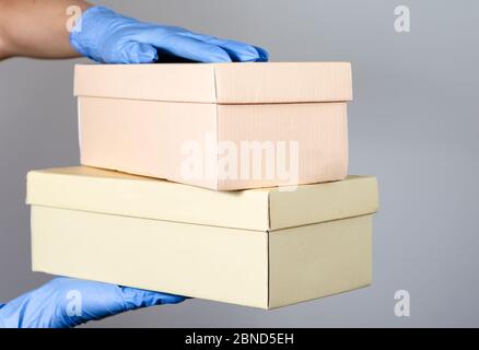 Hände mit chirurgischen Handschuhen einer Frau oder Mann hält mehrere Geschenkboxen Paket . Schutzmaßnahmen für den Vertrieb von Online-Shopping Stockfoto