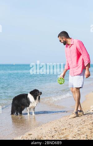 Hund spielt mit jungen Jungen am Strand Stockfoto