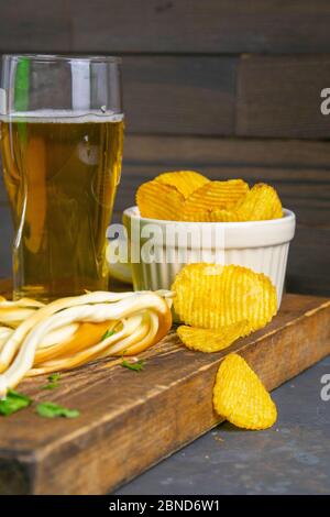 Käse mit Bier, Zitrone und Kartoffelchips auf dunklem Holzbrett. Snack auf Fisch mit Bier. Vorderansicht, Nahaufnahme Stockfoto