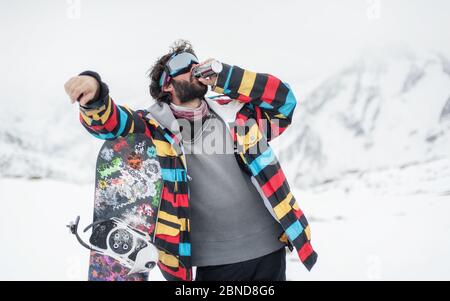 Fröhliche Snowboarder mit Energy Drink im Freien genießen, vor dem Hintergrund der schneebedeckten Gipfel. Travel Lifestyle Konzept aktive Freizeit im Freien von Stockfoto