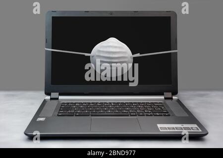 Ein Laptop mit einer Maske. Stockfoto