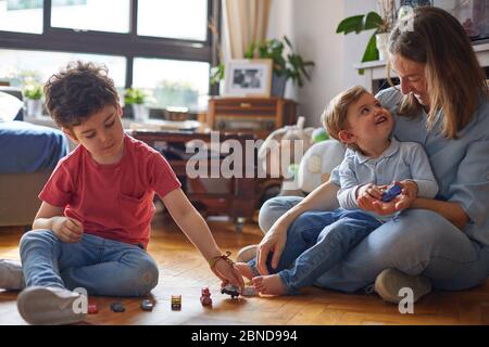 LIEBEVOLLER MOMENT DER GLÜCKLICHEN MUTTER, DIE MIT IHREN KINDERN SPIELT Stockfoto