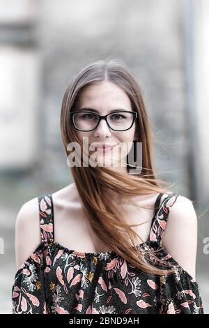 Junge braunhaarige Millennial mit Brille und hellem Kleid Stockfoto