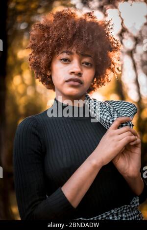 Fröhliche afrohaarige Modell im Inneren sitzend fotografiert Stockfoto