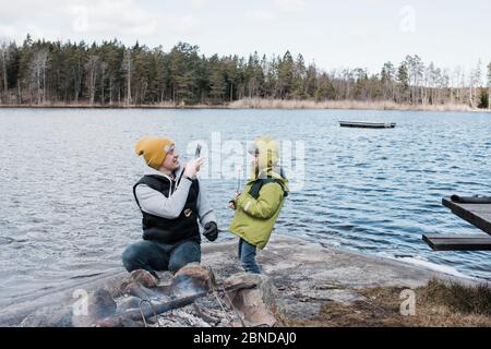 Mann, der ein Foto von seinem Sohn beim Camping beim Essen machte Marshmallows Stockfoto