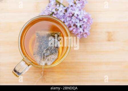 Heißes Getränk in Glas Tasse auf Holztisch. Nahaufnahme Kräutertee in Beutel Tee, Draufsicht Stockfoto