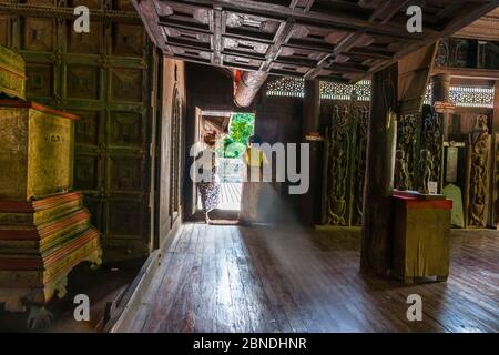 SA Lay Myanmar - Oktober 31 2013; zwei Frauen in Dratitionskleid stehen hinten beleuchtet durch Licht Eingang in Yokesone Kloster historischen hölzernen Bud Stockfoto