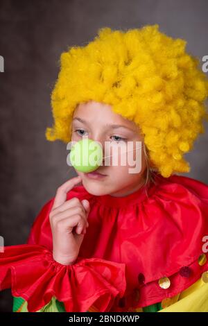 Kleiner Clown in nachdenklicher Stimmung, der Wange mit dem Finger berührt Stockfoto