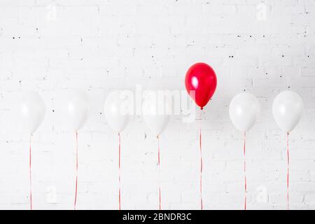 Einzigartiger roter Ballon unter anderem auf weißem Hintergrund Stockfoto