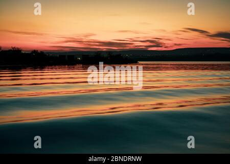 Milde Wellen in einem See während des Sonnenuntergangs mit filmischen Farbgraden Stockfoto