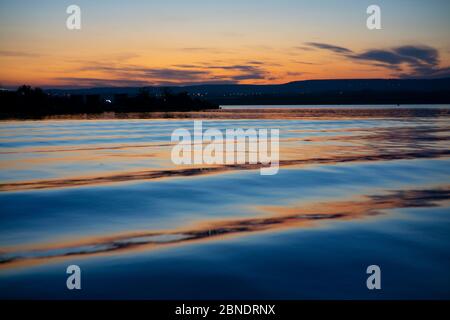 Milde Wellen in einem See während des Sonnenuntergangs mit filmischen Farbgraden Stockfoto