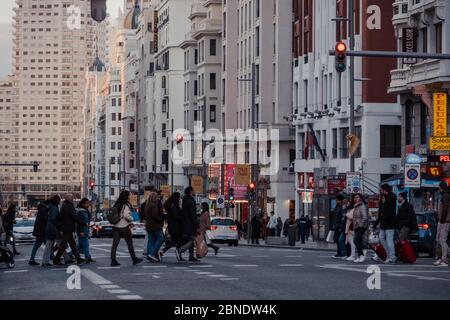 Madrid, Spanien - 26. Januar 2020: Eine große Anzahl von Menschen, die die Gran Via, eine große Straße im Zentrum von Madrid, Spanien, auf einem Fußgängerübergang überqueren, bewegen sich Stockfoto