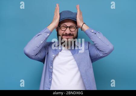 Kaukasische reifen Mann hält Hände auf dem Kopf Gefühl sehr aufgeregt und gestresst. Studio auf blauer Wand gedreht. Stockfoto