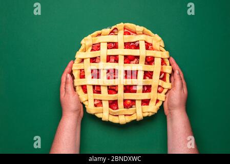 Oben mit Erdbeeren und Rhabarber-Torte. Frau hält in ihren Händen die rohe Torte. Hausgemachte Obsttarte. Stockfoto