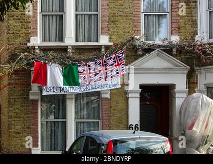 London, Großbritannien - 08. April 2020: Italienische und Union Jack Flaggen mit handgeschriebener Fahne, die Menschen dazu auffordert, zu Hause zu bleiben und die Prävention zu respektieren Stockfoto