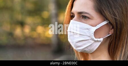 Junge Frau trägt weiße Hause gemacht Baumwolle Virus Mund Nase Maske, schöne Bokeh im Hintergrund, Nahaufnahme Gesicht Porträt, leeren Raum für Text links Stockfoto