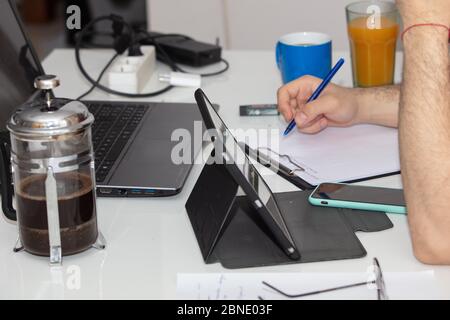 Mann, der zu Hause mit Laptops und Kaffee studiert und arbeitet Auf der Tabelle während der COVID-19-Quarantäne Stockfoto