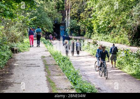 Wanderer, Jogger und Radfahrer trainieren und genießen das warme Wetter auf dem Parkland Walk während der Sperrung der Coronavirus-Pandemie in London, Großbritannien Stockfoto