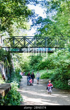 Wanderer genießen das warme Wetter auf dem Parkland Walk, einer stillgelegt Eisenbahnlinie, die heute ein Naturschutzgebiet ist, während der Sperrung der Coronavirus-Pandemie in London, Großbritannien Stockfoto