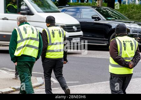 Drei ratsarbeiter ignorieren den sozialen Distanzierungstat, 2 Meter voneinander entfernt zu bleiben, geschrieben auf der Rückseite ihrer gut sichtbaren Jacken, London, Großbritannien Stockfoto