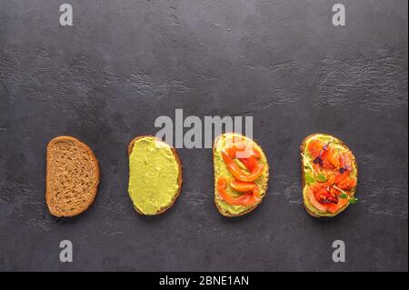 Stufen der Herstellung eines Sandwich von Brot, Guacamole, gesalzenem Lachs, gebackene Tomaten und Grüns Stockfoto