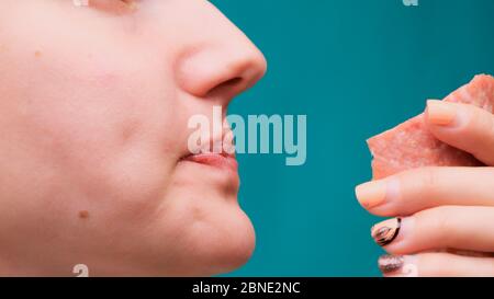 Nahaufnahme einer Frau, die auf einem grünen Bildschirm eine Wurst beißt. Ungesunde Ernährung und Diät-Konzept Stockfoto