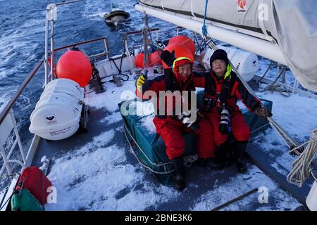 Zwei chinesische Walbeobachter sitzen auf einem Boot, in der Nähe von Senja, Troms County, Norwegen, Skandinavien, Januar 2015. Stockfoto