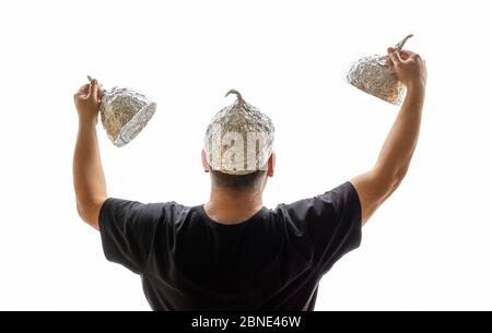 Mann mit Aluminiumhut auf dem Kopf und in jeder Hand ein anderer Aluminiumhut vor weißem Hintergrund Stockfoto