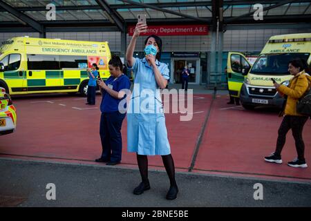 NHS-Mitarbeiter vor dem Queen Elizabeth Hospital in Birmingham, als sie sich dem Applaus anschließen, um lokale Helden während des landesweiten Clap für Betreuer zu begrüßen, um NHS-Mitarbeiter und Betreuer zu unterstützen, die gegen die Coronavirus-Pandemie kämpfen. Stockfoto