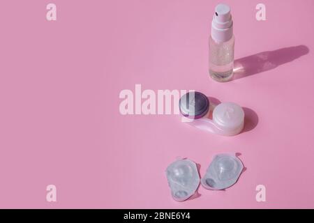 Kontaktlinse-Kit. Der pinke Tisch ist ein Spray zum Desinfizieren von Händen, Behälter für die Linsen und Blasen mit Linsen. Stockfoto